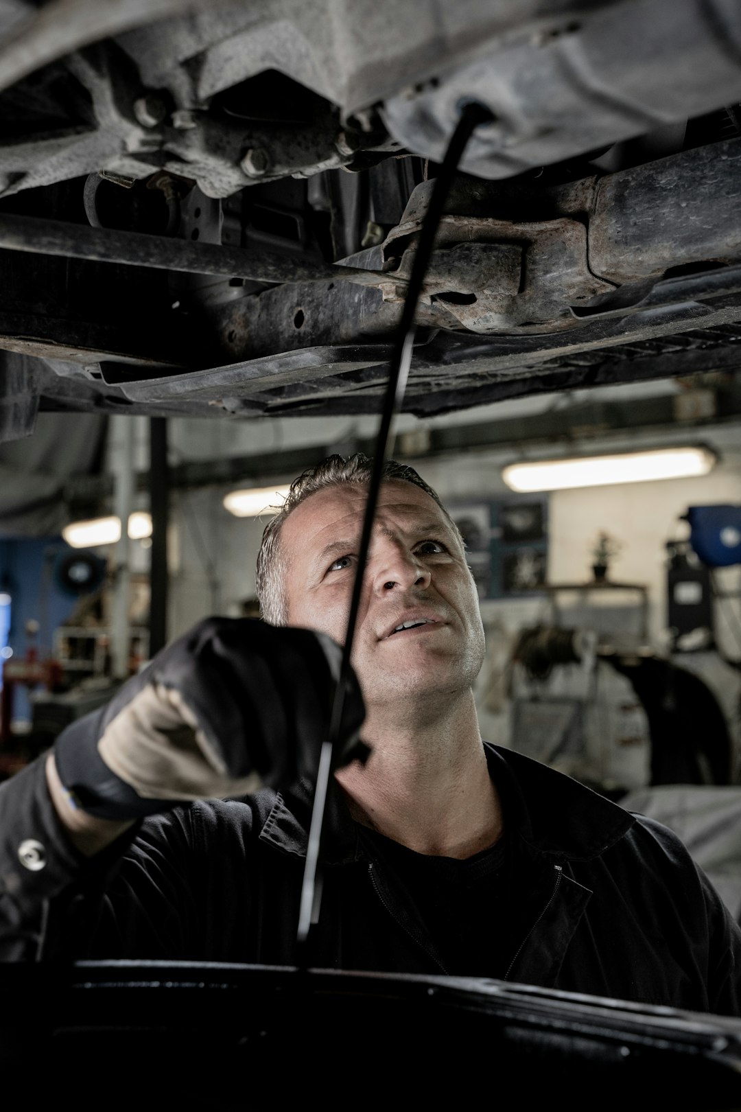 A mechanic changes oil in a car.