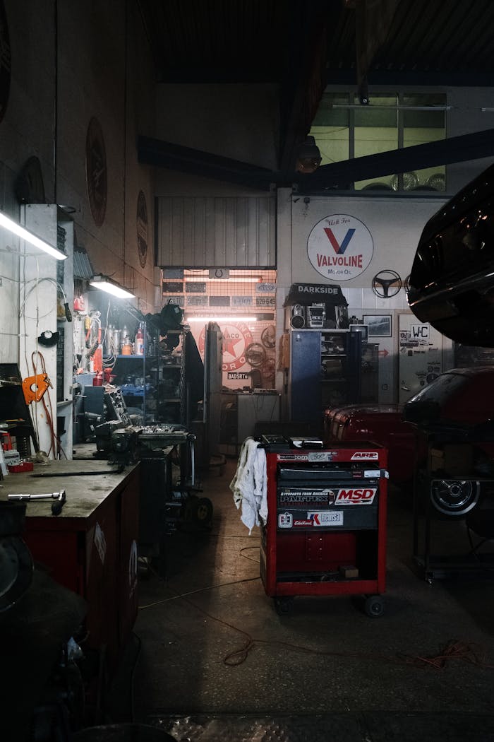 Dimly lit industrial garage filled with car repair tools and machinery, ideal for automotive themes.